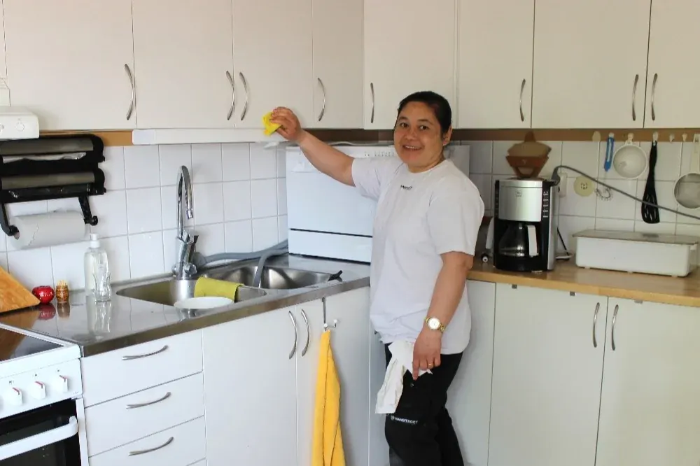 Medarbetare torkar av köksskåp hemma hos en kund
